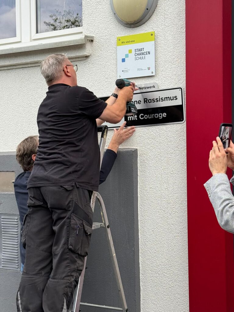feierliche Anbringung des Schildes an der Fassade der Schule durch Hausmeister Martin Hökendorf